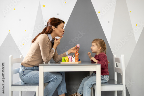 Εκτύπωση καμβά Speech therapist guiding a young girl through playful oral-motor exercises with