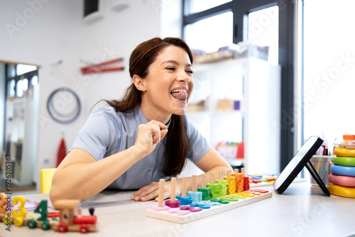 Speech language pathologist demonstrating tongue exercises during a therapy session, helping with articulation, speech development, and oral motor skills in a clinic setting