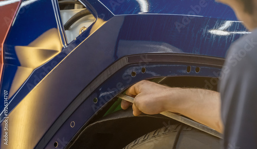 Process of paintless dent repair on car body. The mechanic at the auto shop with tools to repair dents in car body. Body repair. PDR. A specialist repairs a dent on the car body without painting.