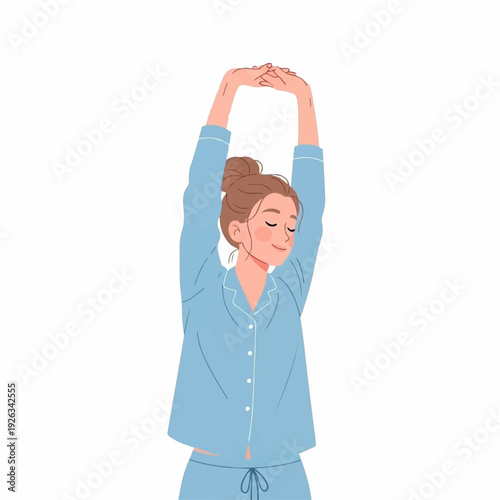Young woman in blue pajamas stretches her arms high above her head while waking up in the morning.