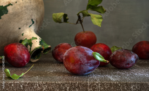 Still life with ripe and delicious plums, an apple and an old ceramic jug.