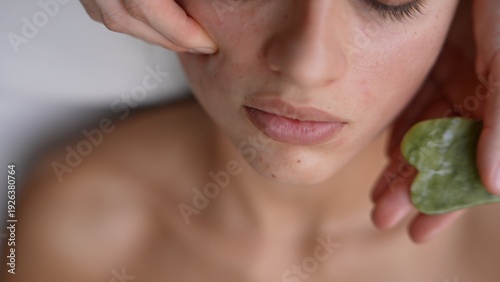 Spa esthetician performing jade facial treatment on woman