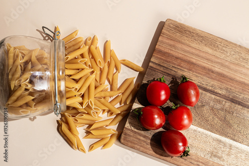  Spilled Penne Pasta and Fresh Cherry Tomatoes on Wooden Board