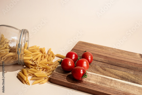  Spilled Penne Pasta and Fresh Cherry Tomatoes on Wooden Board