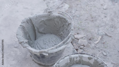 Close up of fresh cement mortar being poured and mixed in bucket at construction site. Building renovation, masonry preparation and industrial material concept.