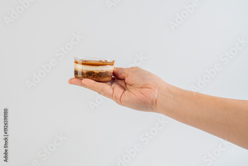 Wallpaper Mural Three-layered brownie cake topped with crunchy topping in a clear cup and hand. Torontodigital.ca