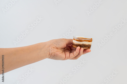 Wallpaper Mural Three-layered brownie cake topped with crunchy topping in a clear cup and hand. Torontodigital.ca