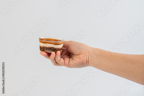 Wallpaper Mural Three-layered brownie cake topped with crunchy topping in a clear cup and hand. Torontodigital.ca