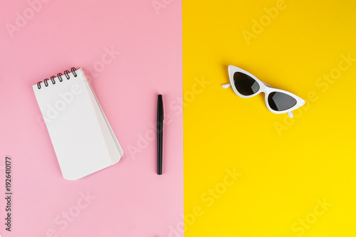 Wallpaper Mural Fashionable sunglasses with a notebook and stationery, against a yellow and pink background. Torontodigital.ca