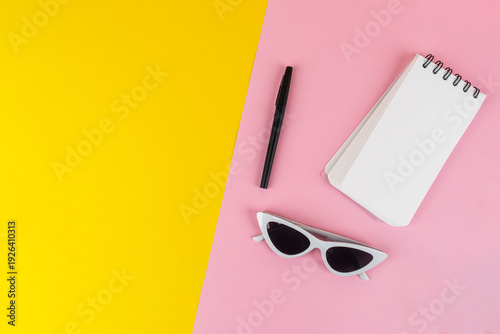 Wallpaper Mural Fashionable sunglasses with a notebook and stationery, against a yellow and pink background. Torontodigital.ca