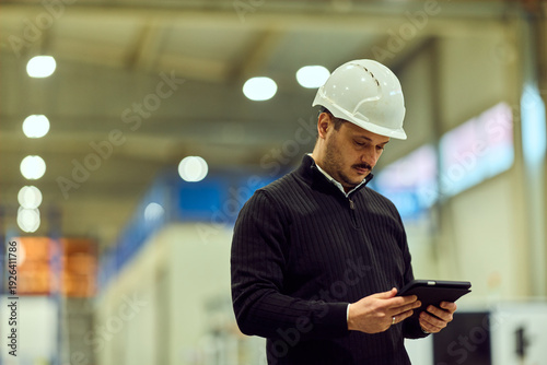Warehouse Site Manager Wearing Hard Hat Using Tablet for Safety Inspection and Operations Management