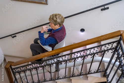 Wallpaper Mural Disabled woman seated on home stairlift gliding smoothly down staircase with safety belt engaged Torontodigital.ca
