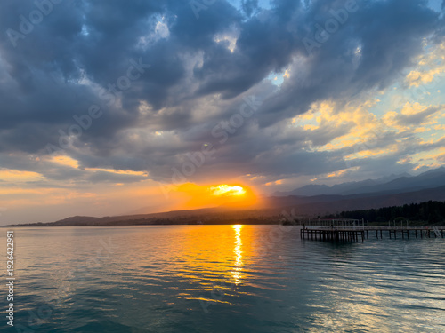 Wallpaper Mural Sunset at Issyk Kul Lake in Kyrgyzstan. Bright sun breaking through clouds reflecting in clear turquoise water. Torontodigital.ca