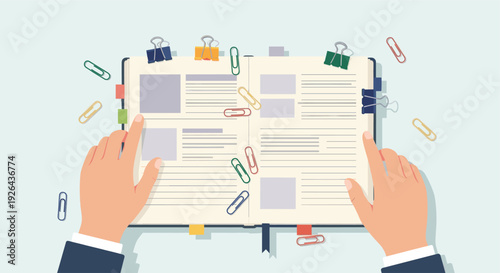 An overhead shot of hands using an open notebook with scattered colorful paperclips, creating a bright and organized workspace for planning or note-taking activities.