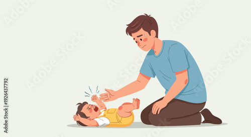 A young father kneels to comfort his crying baby, who is lying on the floor wearing a yellow romper; the scene conveys a mix of concern and gentle care.