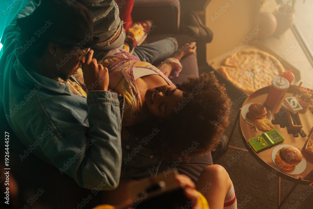 Obraz premium Retro friends cuddling on a couch during a cozy 90s movie night with pizza and games