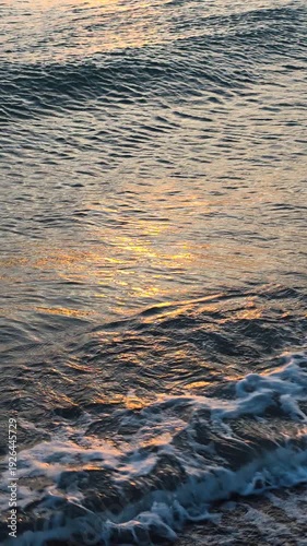 Golden sun reflecting on gentle ocean waves during a serene sunset, creating a tranquil and mesmerizing background with shimmering light on the dark water surface