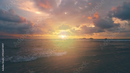 Dramatic sunset over the ocean with colorful clouds and gentle waves, creating a serene and tranquil atmosphere, premium quality 4K animation for creative projects.