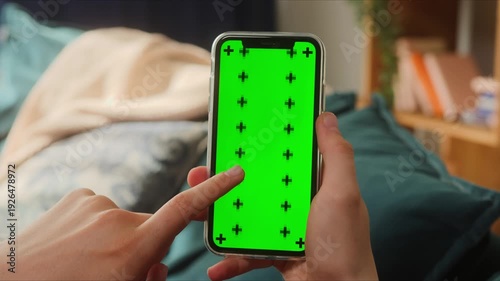 Hands holding a smartphone with a green screen and tracking markers for editing, 4K animated visual for modern digital content.