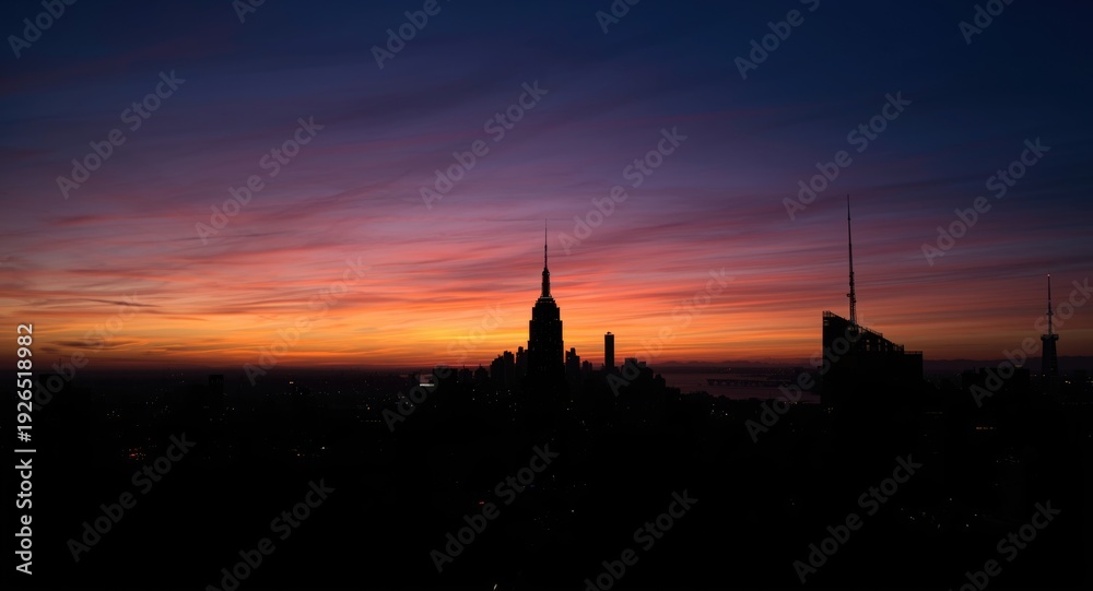 Naklejka premium Silhouetted skyscrapers against a colorful evening sky