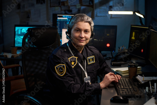 Tableau sur toile Portrait of middle aged Caucasian woman police officer sitting at desk, wearing