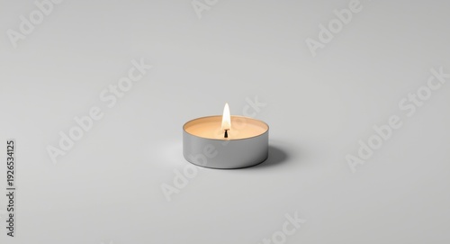 Solo paraffin wax tealight candle displaying warm glow against a stark white background