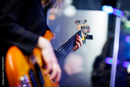 Musician playing electric bass guitar at live concert