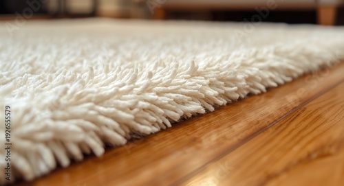 Detailed view of a soft white shag rug on a smooth varnished timber floor with ambient light