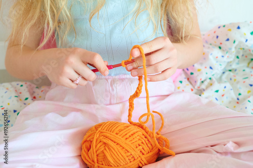 Photography Girl crocheting with yarn on bed