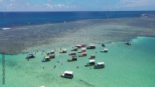 Amazing view of dozens of small boats in the natural pools among the coral reefs of Milagres beach near Maceio city, coast of Brazil 