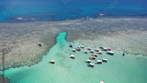 Amazing view of dozens of small boats in the natural pools among the coral reefs of Milagres beach near Maceio city, coast of Brazil 