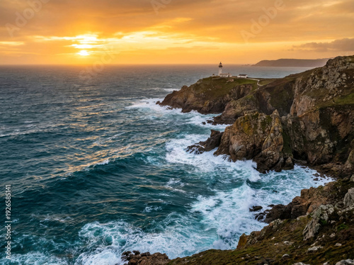 Dramatic sunset over a rugged coastline with a lighthouse guiding ships through the choppy sea.