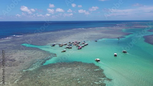 Amazing view of dozens of small boats in the natural pools among the coral reefs of Milagres beach near Maceio city, coast of Brazil 
