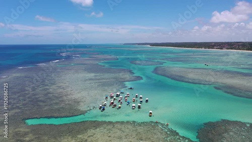 Amazing view of dozens of small boats in the natural pools among the coral reefs of Milagres beach near Maceio city, coast of Brazil 