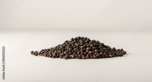 loose black peppercorns stacked on neutral white background