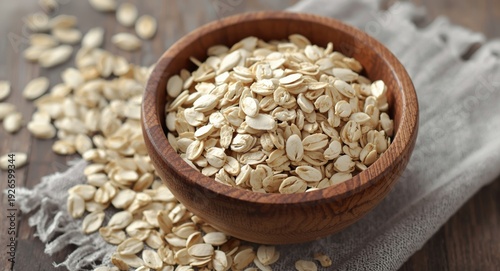 Wooden bowl presenting raw rolled oats blended with oat flakes on table
