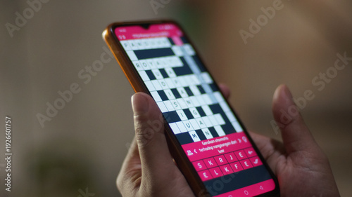 Wallpaper Mural Close-up of a person's hand using his cell phone to do a crossword puzzle, utilizing technology for cognitive stimulation Torontodigital.ca