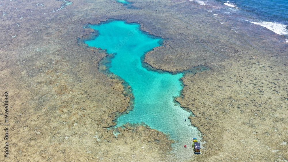 Obraz premium Fantastic aerial view of the turquoise waters of Toque beach with dozen of small boats with tourists on the natural pools formed among coral reefs in Milagres route near Maceio, Alagoas State, Brazil 