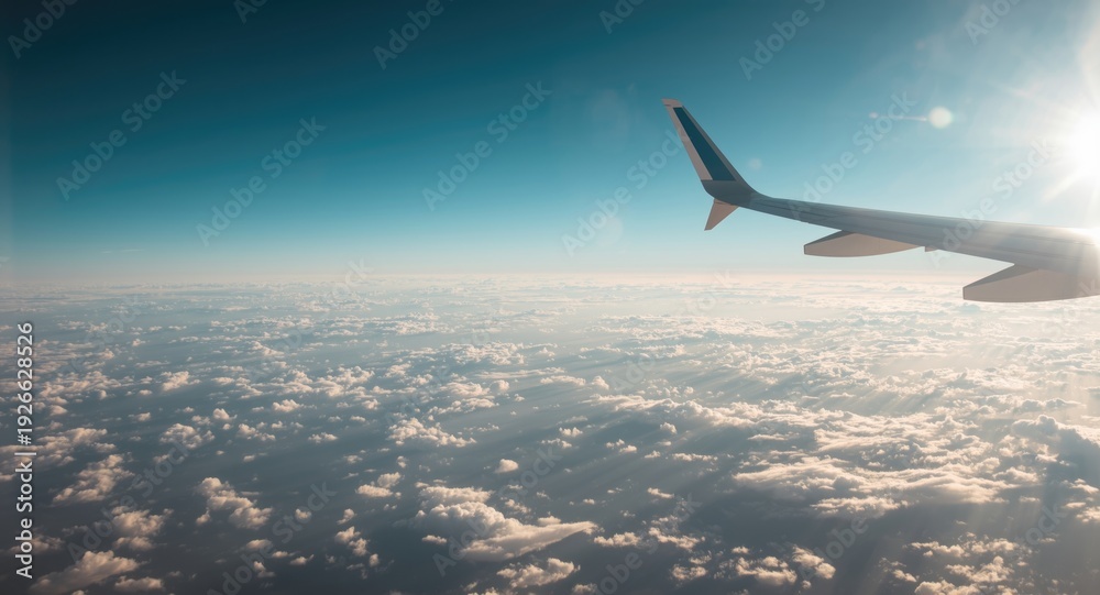 Fototapeta premium Aerial view from airplane wing flying through a blue sky with soft cloud clusters