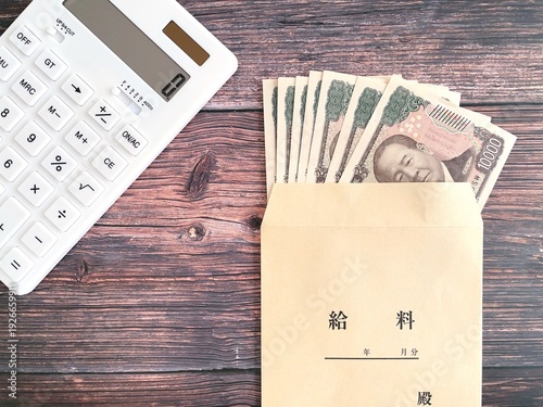 Fotografie Japanese Salary Envelope with Yen Banknotes and Calculator on Wooden Table