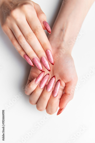 Woman's hands showing long pink glitter stiletto nails