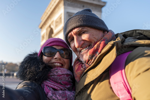 Senior couple enjoying paris vacation, smiling for a selfie near arc de triomphe
