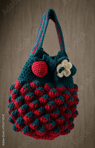 Crocheted Strawberry-Shaped Bag Against a Light Brick or Textured Plaster Wall.