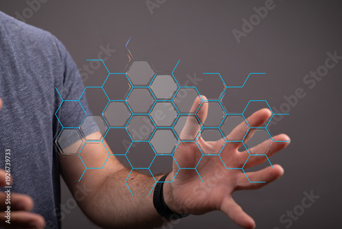 Close-up of a man's hand interacting with a digital hexagon grid, representing technology and connection in the modern a