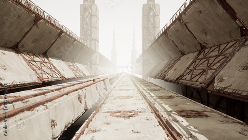 Billede på lærred Sunlit rusted transit corridor leading to bright horizon framed by towering conc