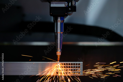 Close up automation laser cutting machine working with metalwork is drilling holes metal rods it causing sparks on industrial factory, copy space
