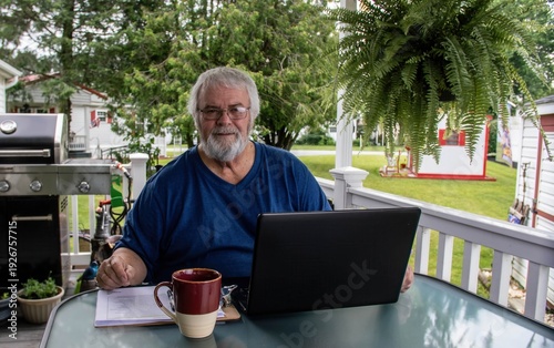 Foto A man sits at a table outdoors, working on his laptop