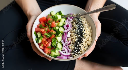 Female chef preparing a fresh gourmet vegetarian salad with tomatoes peppers and lettuce on a plate of rice in a restaurant kitchen