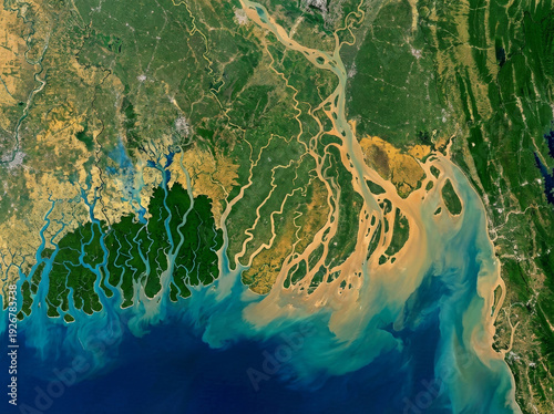 Aerial view of the Ganges Delta, a vast river system meeting the ocean, showcasing intricate waterways and lush green vegetation.