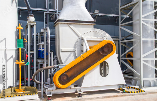 Fotografie Industrial centrifugal fan blower with motor and orange belt guard in a modern factory